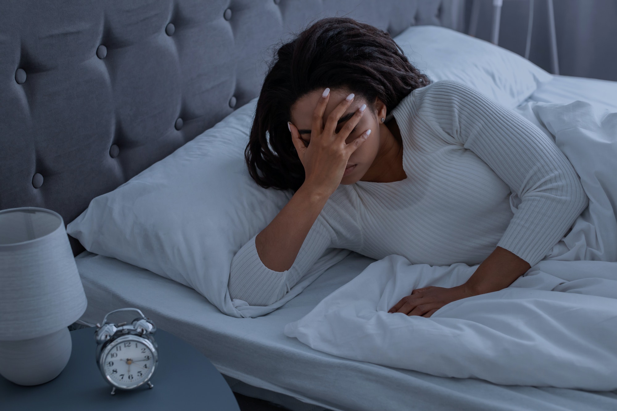 Black woman suffering from insomnia covering face