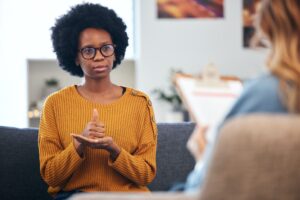 Sign language, speech therapy and black woman talking to therapist in a consultation or counseling