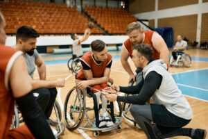 Disabled basketball team and their coach analyzing game strategy during wheelchair basketball match.